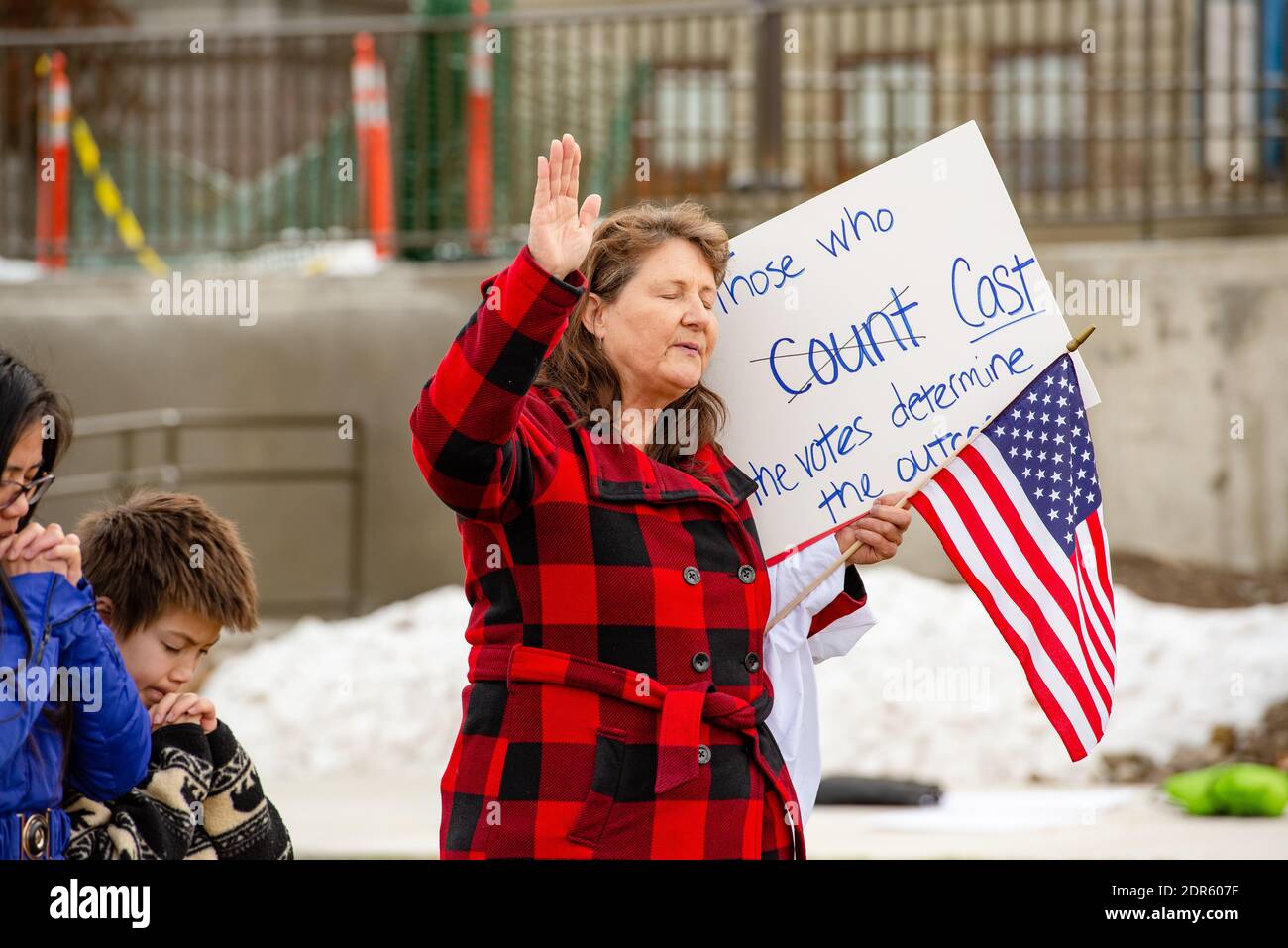 Helena, Montana / Nov 7, 2020: Woman and children praying raising hand at Donald Trump's Stop the Steal rally holding American flag and sign about cou Stock Photo
