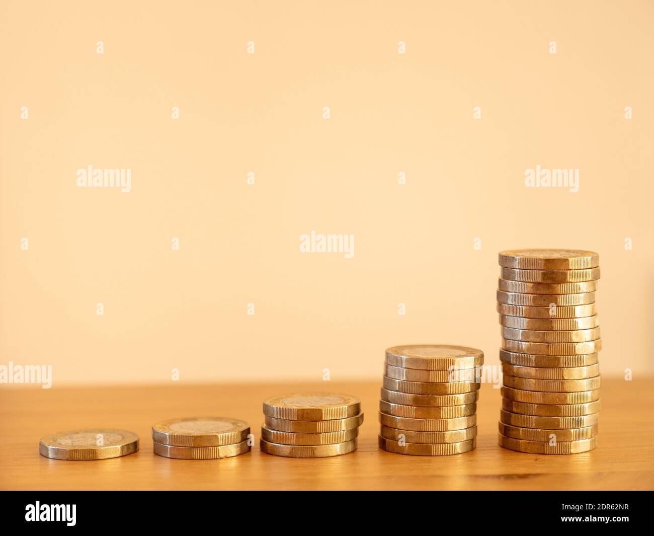 Close up of stacks of many GBP one pound coins increasing in size as money going up symbolising saving wealth, UK Stock Photo