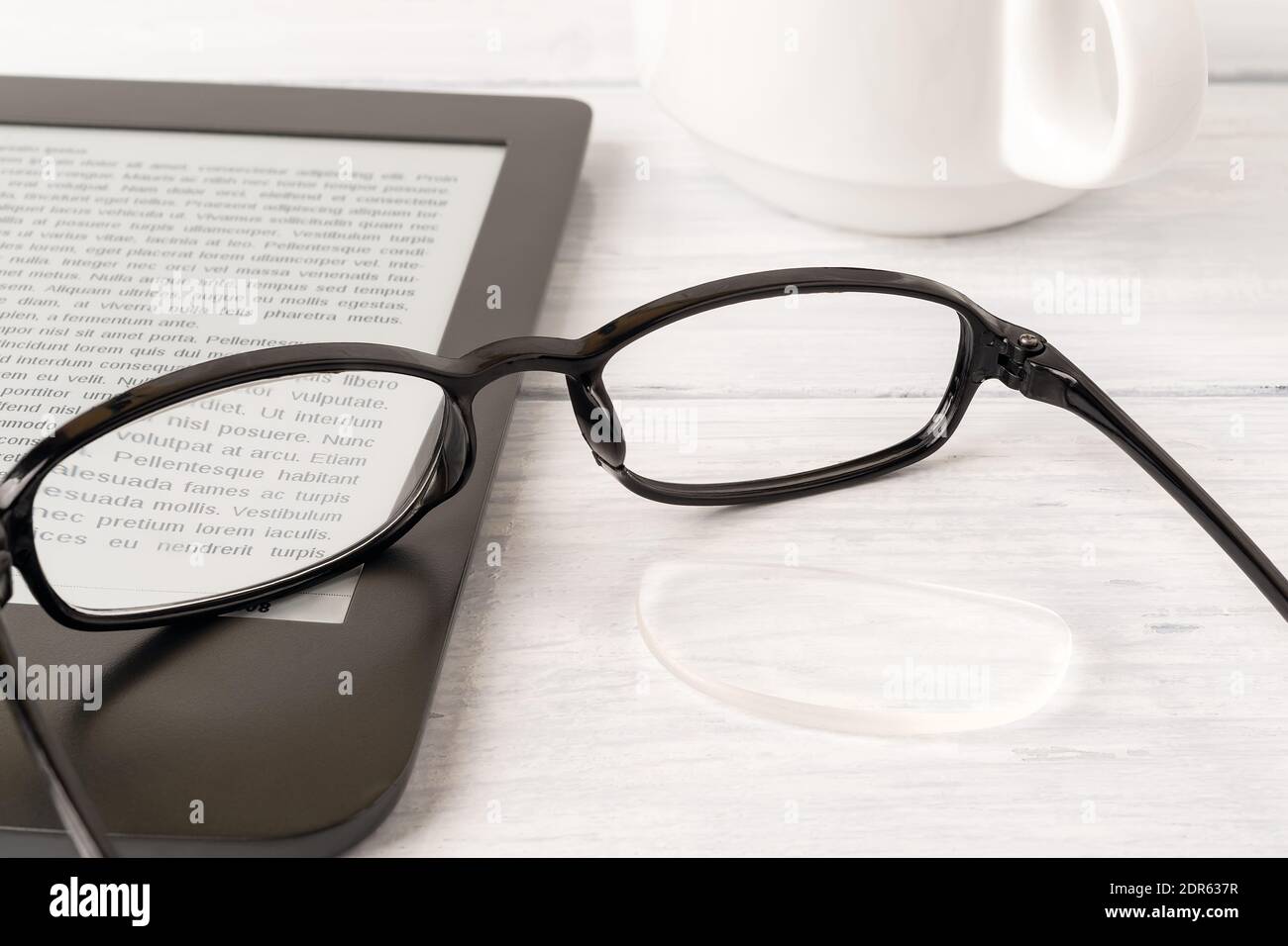 Eyeglasses with one lens fell down from the rim on a ereader over