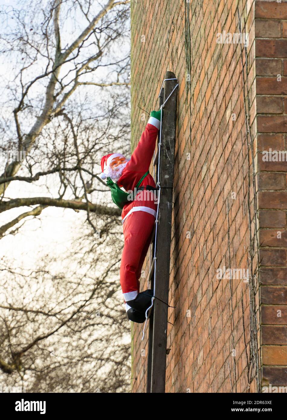 Father Christmas figure climbing a ladder Stock Photo