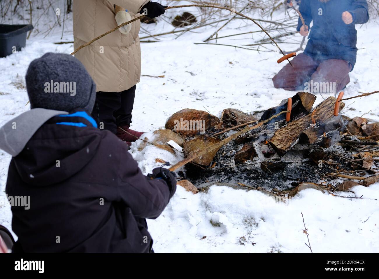 People roasting hot dogs over an open fire outdoors in the snow in winter in Ottawa, Ontario, Canada. Stock Photo