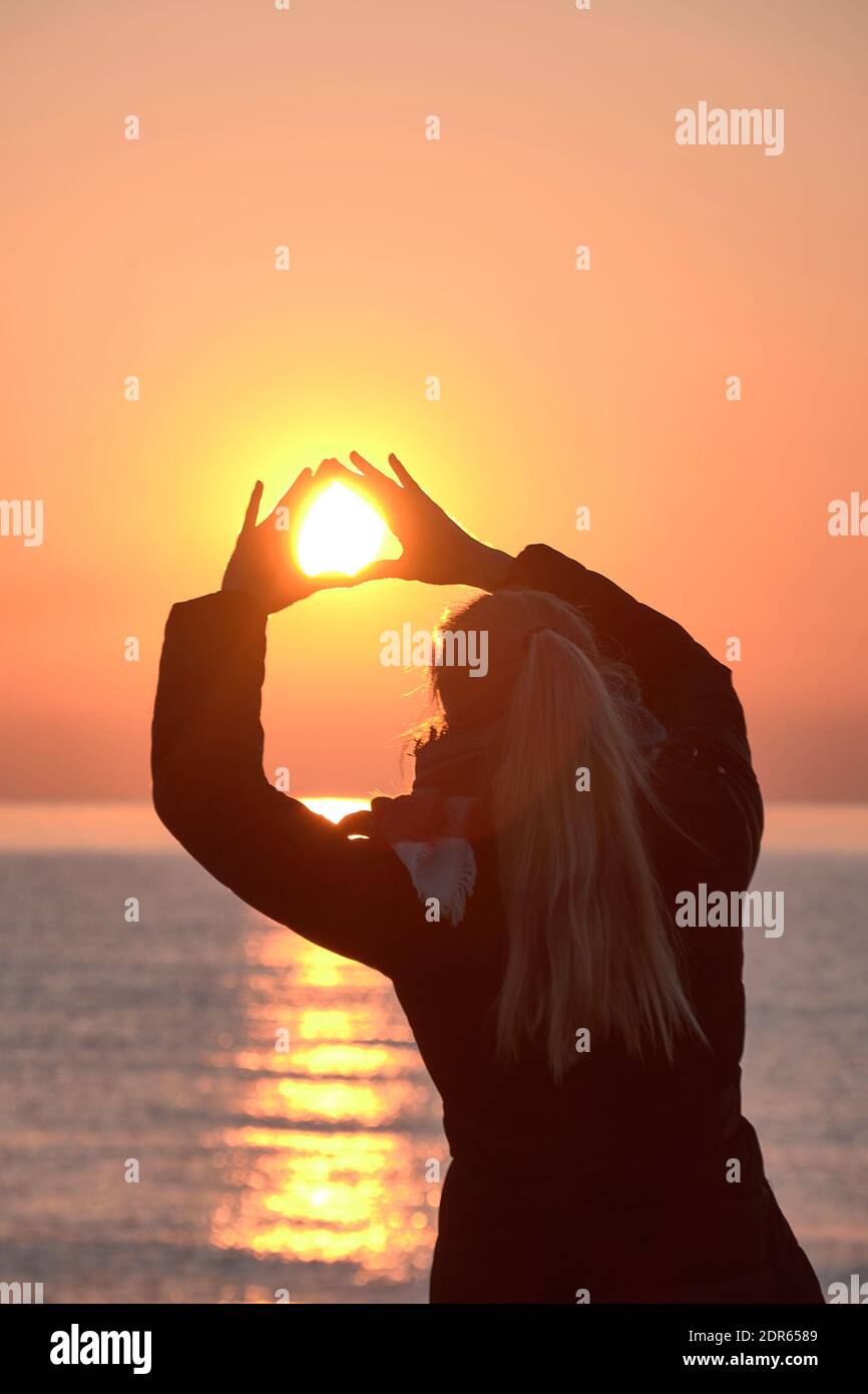 Blonde girl from the back catching the sun, sunrise, no clouds, black