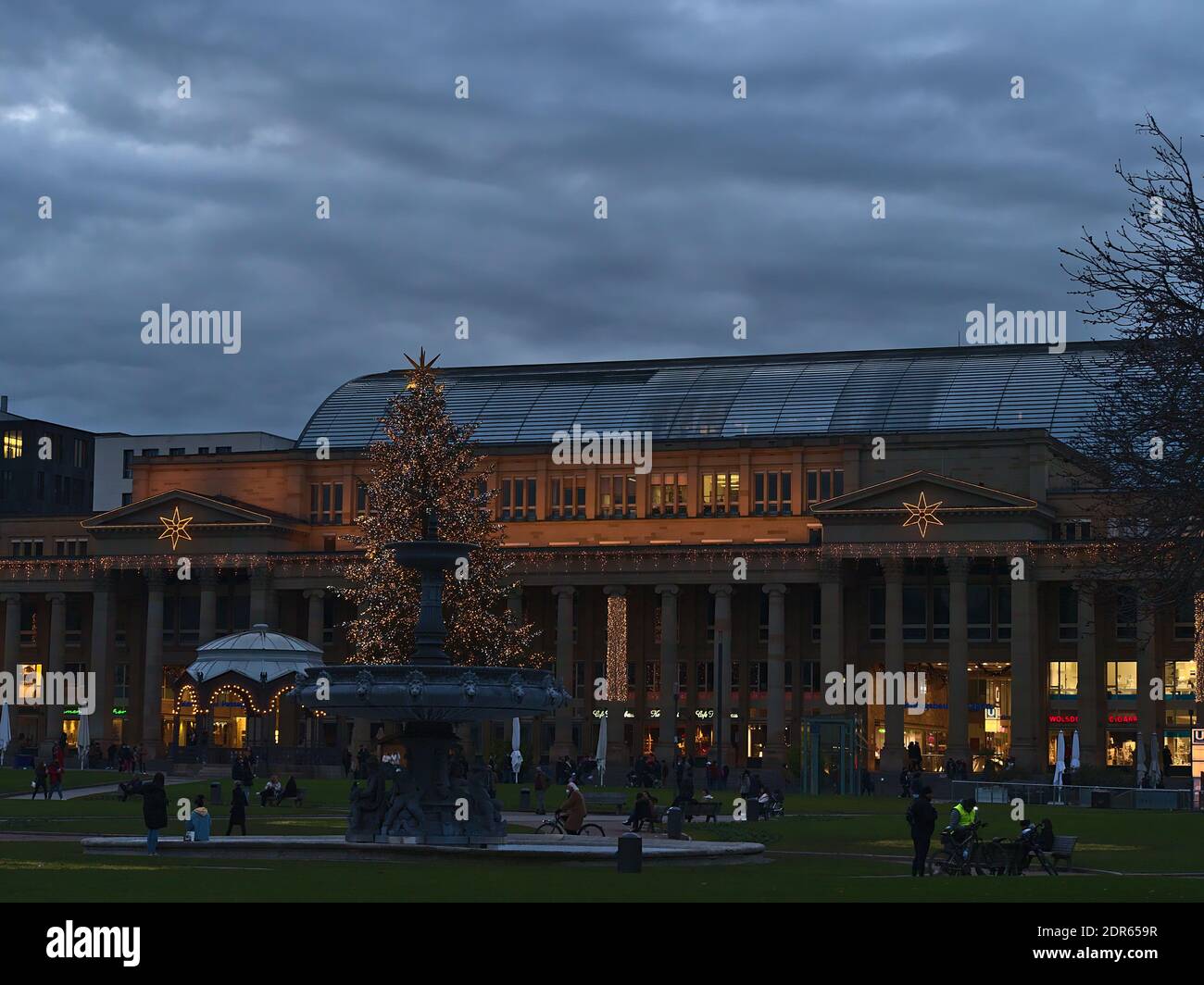 People relaxing on popular square Schlossplatz in city center in front of historic building Königsbau during Christmas time with decorations. Stock Photo