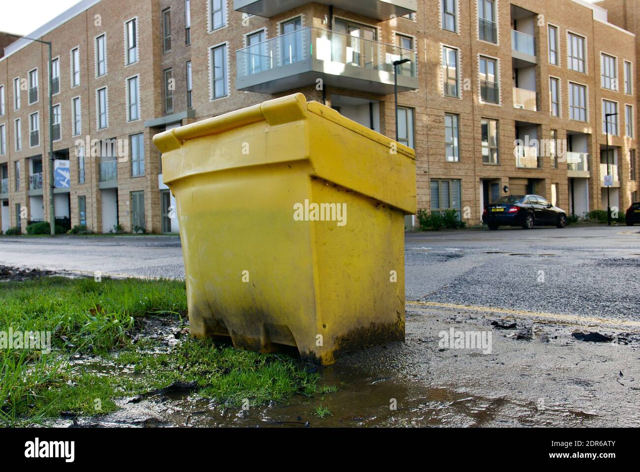 Yellow grit salt container bin side of road in London. England often struggles to cope with cold snaps and icy roads due to salt shortage. Stock Photo