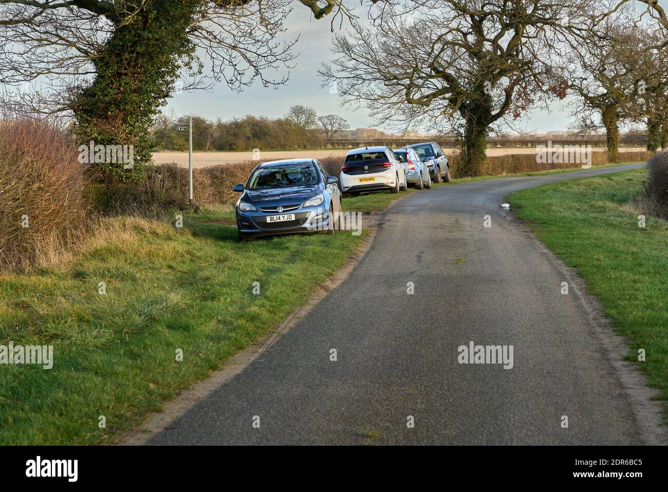 Row of cars parked on a countryside grass verge next to a bridleway leading from a minor road near Pickworth in Lincolnshire Stock Photo