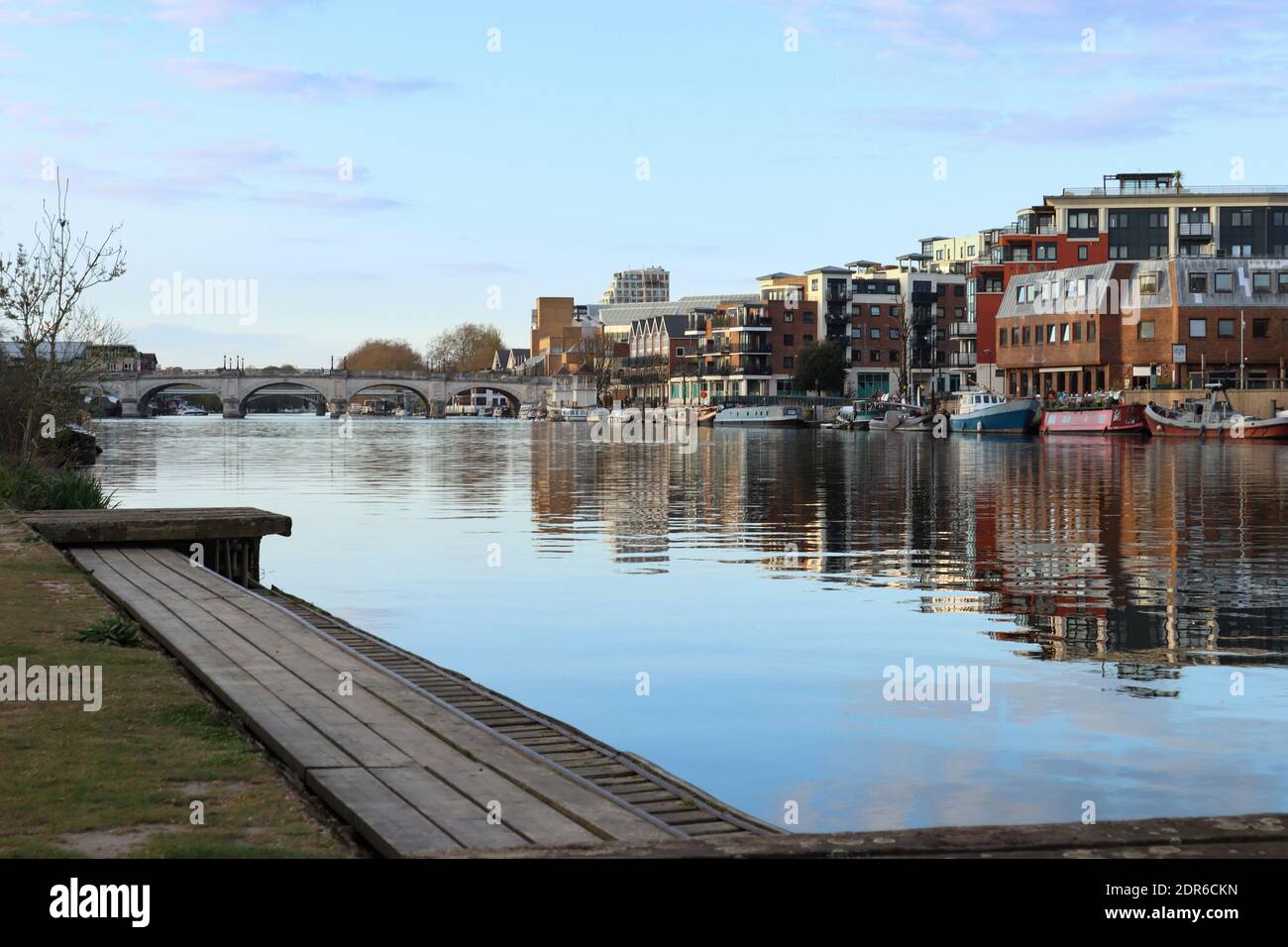 Kingston Upon Thames quayside and bridge, and their reflection on to the river Thames, on a sunny blue sky spring evening Stock Photo