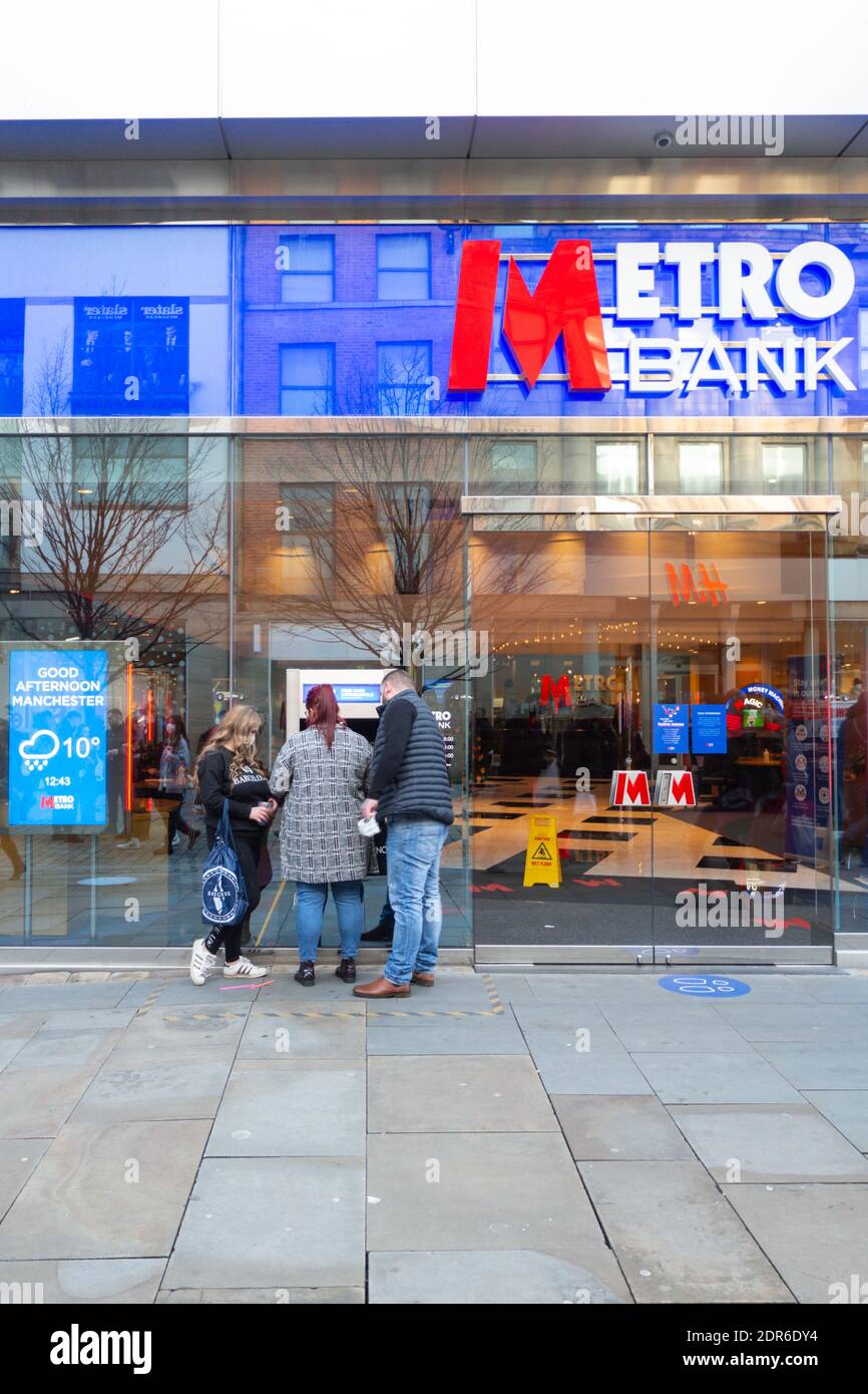 Metro Bank storefront or facade, Market Street, Manchester City Centre. Three people use an atm or cash machine. December 2020 Stock Photo