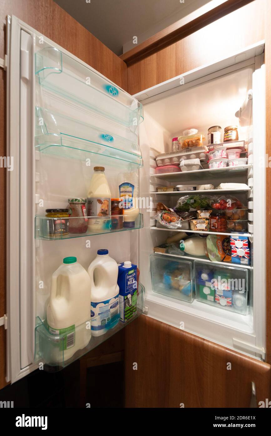 UK fridge or refrigerator with door open showing contents inside. Stocked up, supplies
