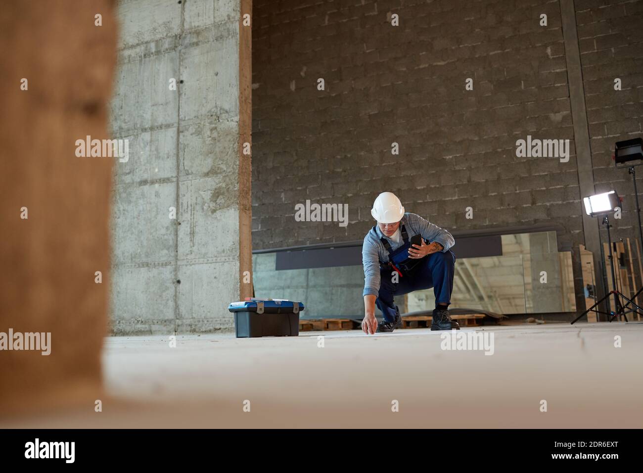 Wide angle view of female construction worker marking floor while working in apartment building, copy space Stock Photo