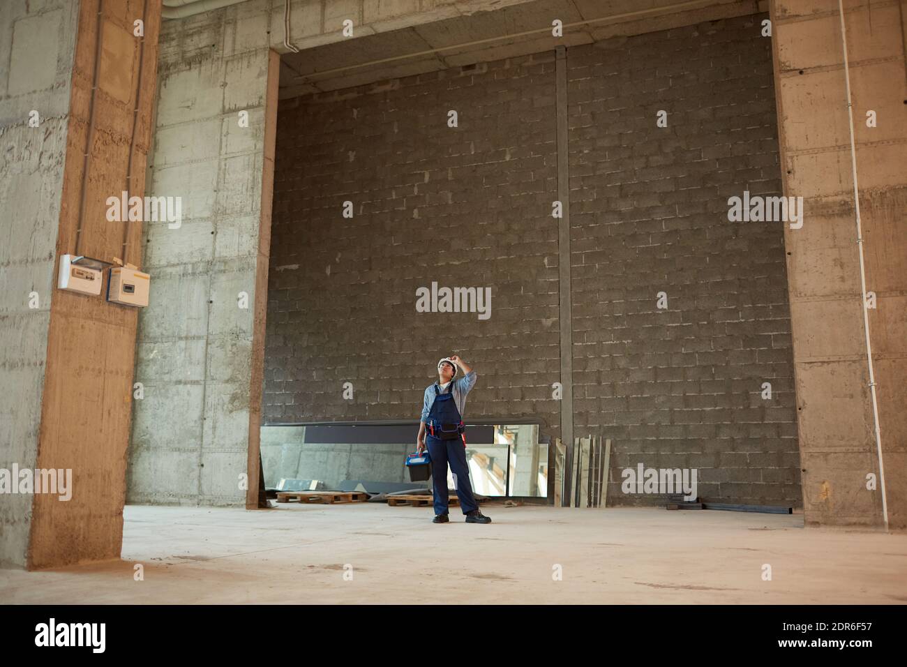 Wide angle view of female construction worker wearing hardhat while standing in big concrete archway, copy space Stock Photo