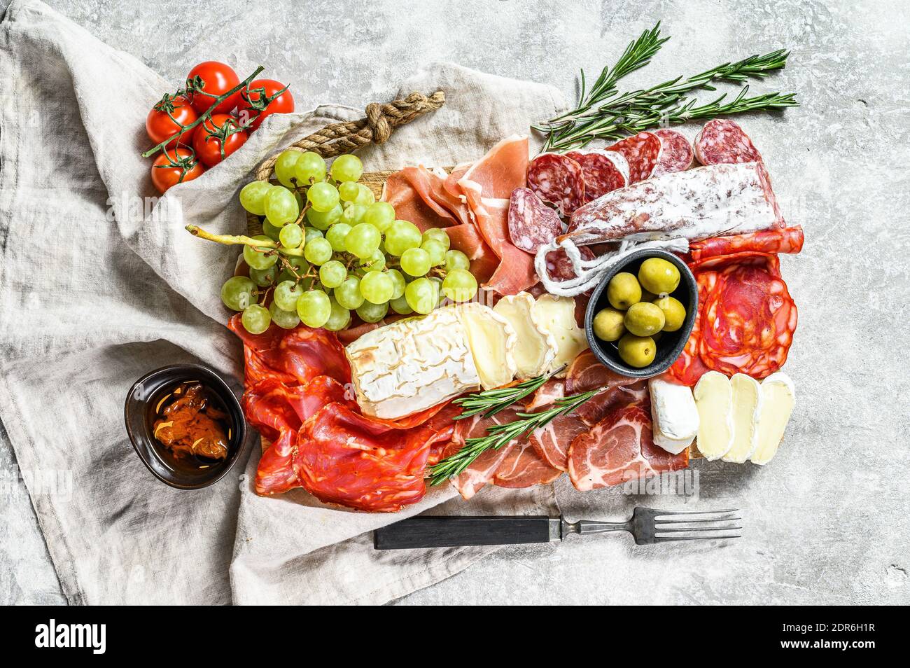 Italian antipasto, wooden cutting board with prosciutto, ham, parma