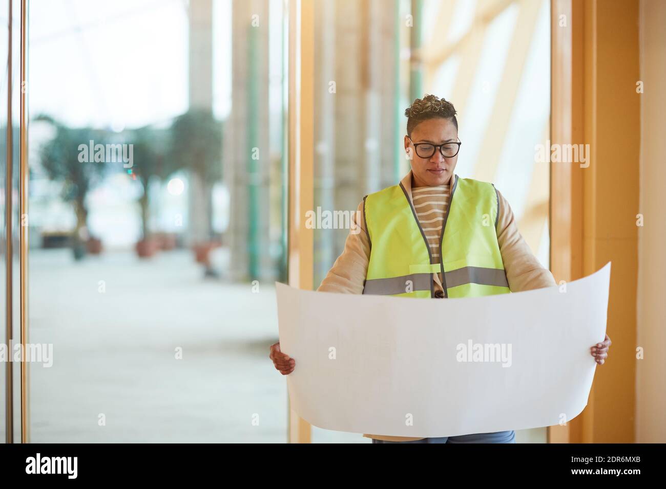 Waist up portrait of contemporary female engineer looking at blueprints while designing architectural project, copy space Stock Photo
