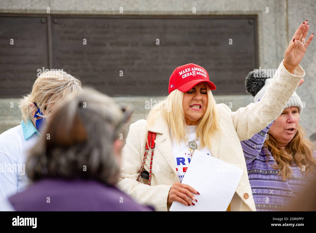 Helena, Montana - Nov 7, 2020: Woman wearing red Make America Great Again hat praying at Stop the Steal rally in support of Donald Trump, perceives th Stock Photo