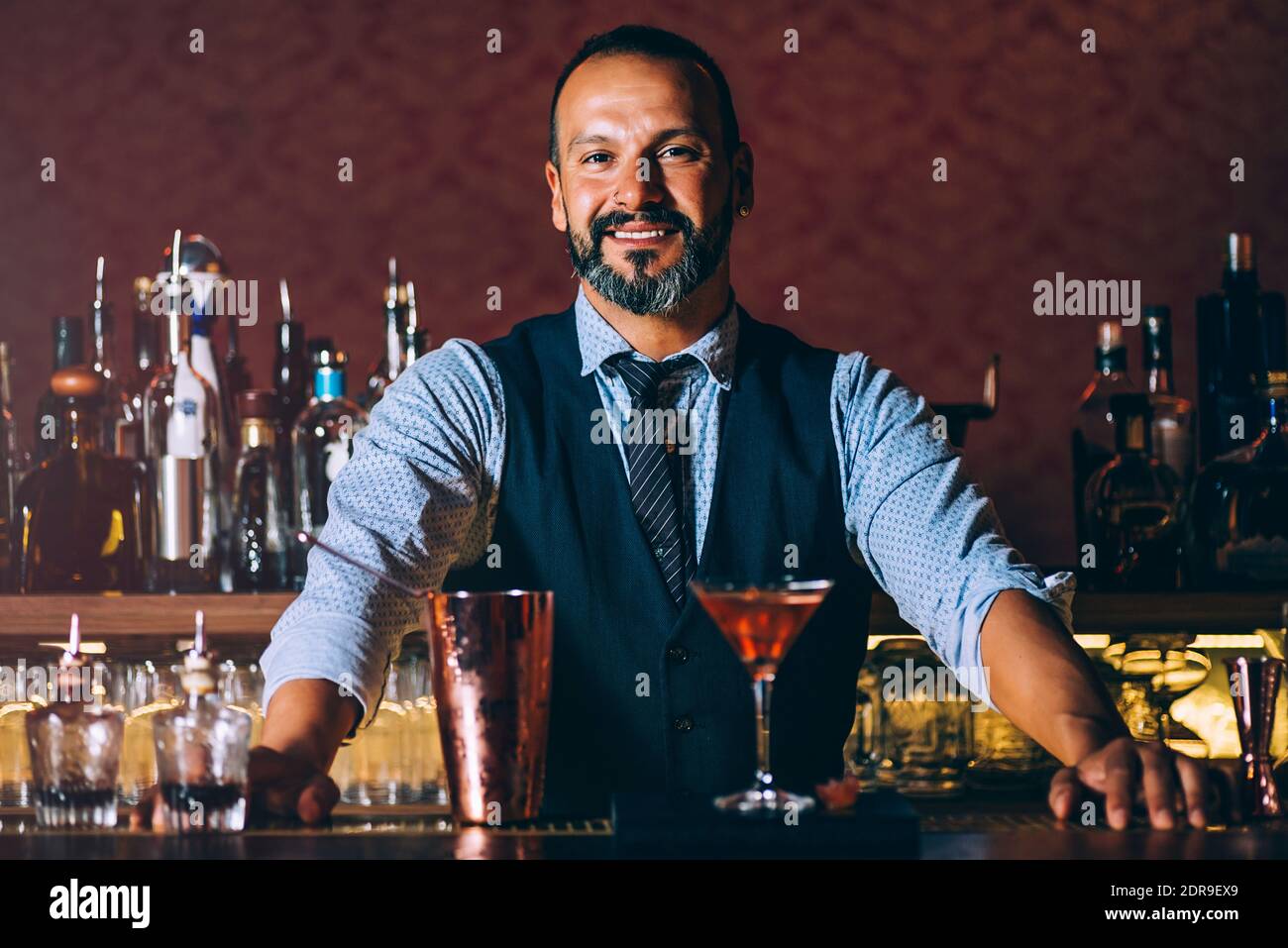 Portrait Of Smiling Mature Bartender Standing By Cocktail On Bar Counter  Stock Photo - Alamy