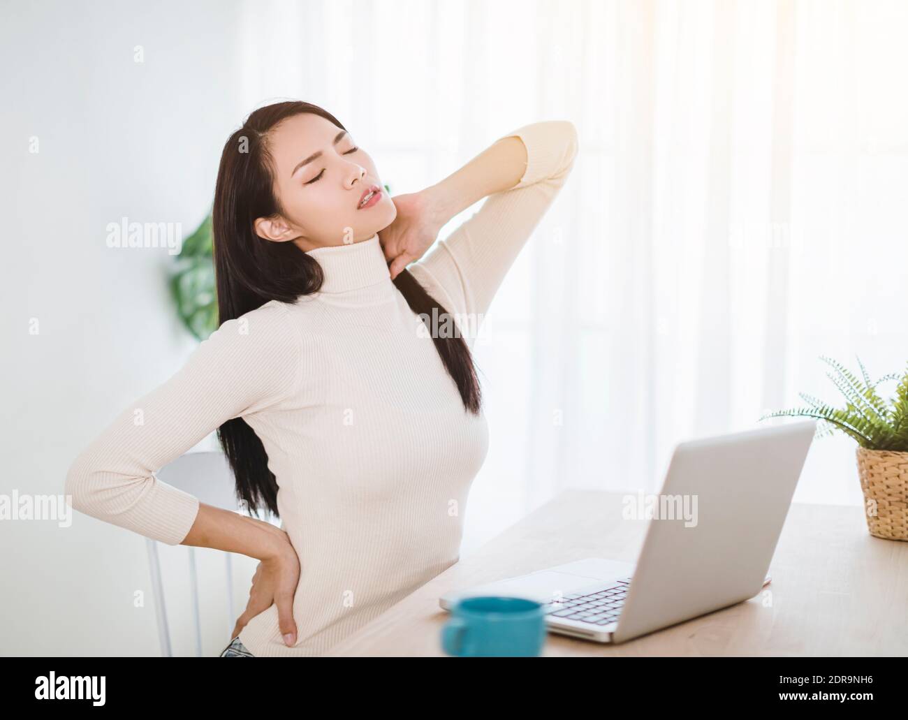 young woman with neck pain and massaging neck while working in office at home Stock Photo Alamy
