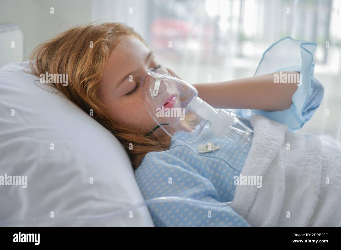 Girl Wearing Oxygen Mask While Lying On Bed In Hospital Ward Stock