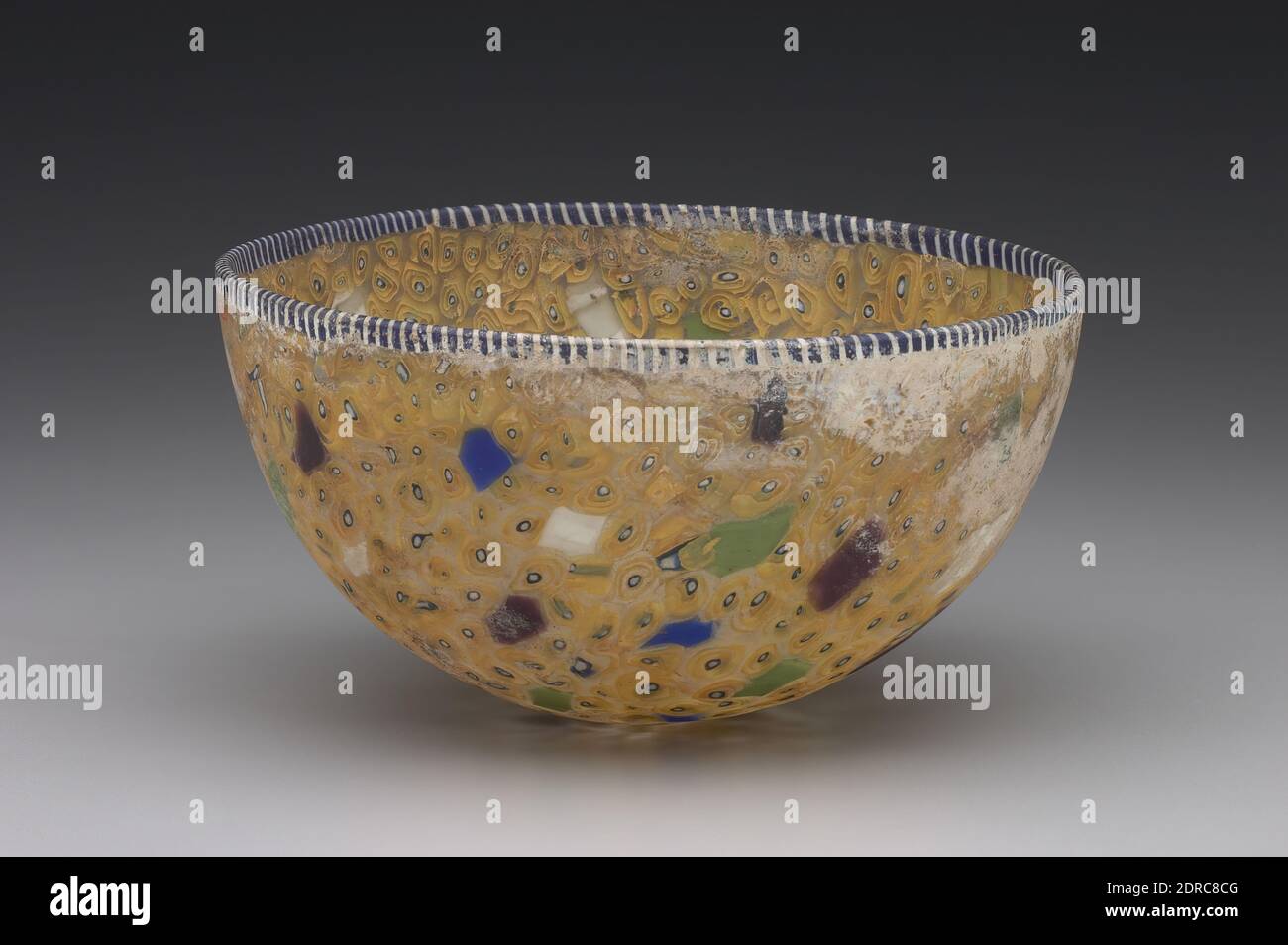 Bowl, Late 2nd century B.C.–early 1st century A.D., Cast mosaic glass, 7.8 × 14.1 cm (3 1/16 × 5 9/16 in.), This hemispherical bowl is an example of ancient mosaic glass, a type of highly colorful glassware that attained its greatest popularity in the second and first centuries B.C. The mosaic decoration (sometimes anachronistically called millefiori after Venetian glass decorated in the same way) was achieved by arranging separate pieces of glass–often with colorful patterns already worked into them–in a mold and fusing them with heat in an oven or kiln. Stock Photo