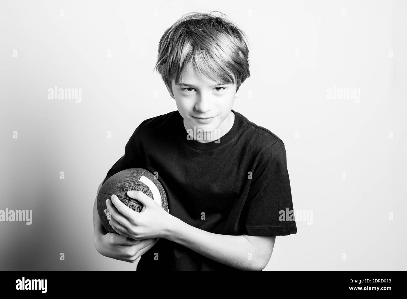 Portrait Of Teenage Boy Holding Rugby Ball Against White Background