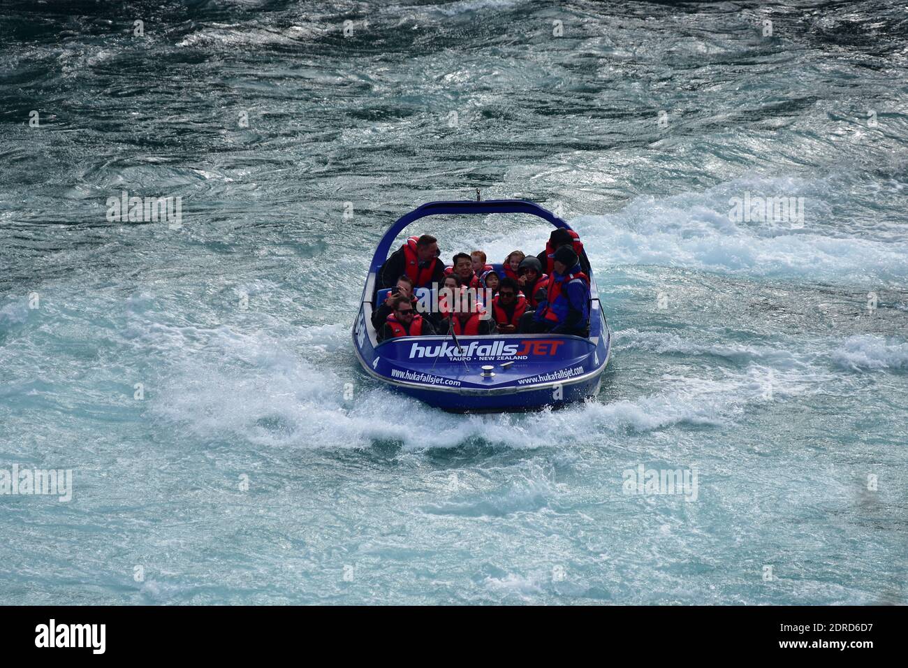 Front view of Huka Falls jet boat with tourists on board in fast moving water. Stock Photo
