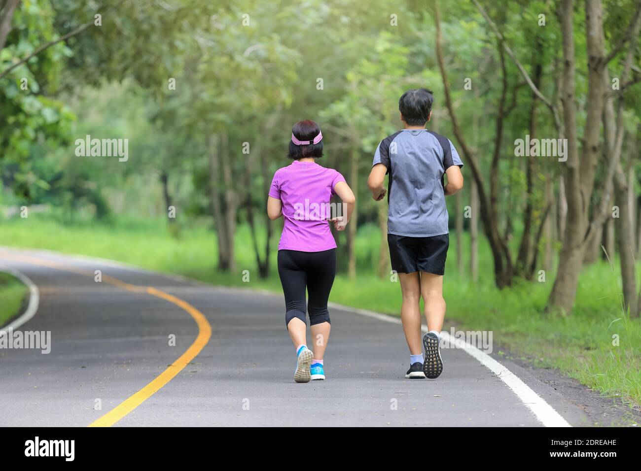 Asian middle aged couple jogging and running in park Stock Photo - Alamy