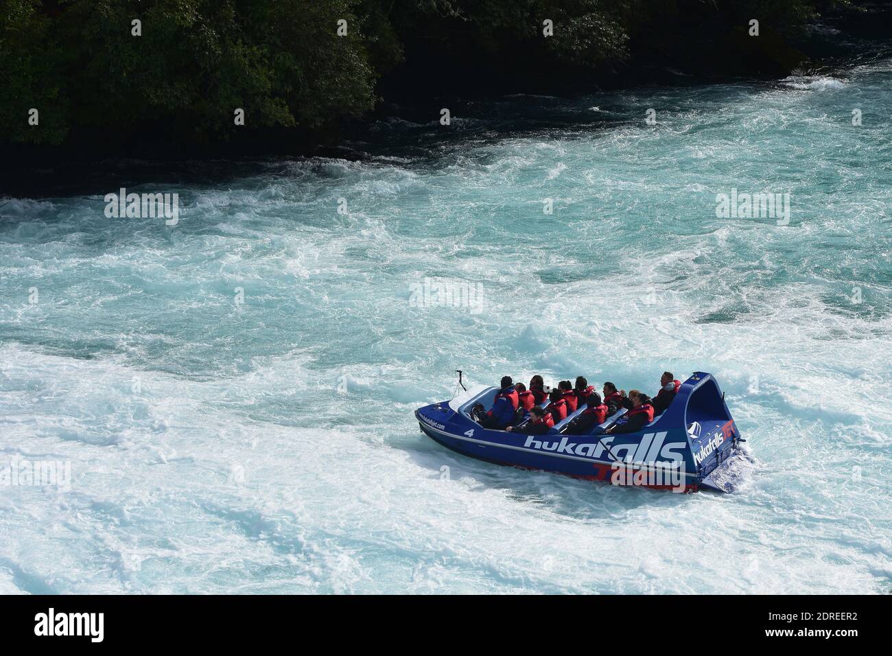 Tourist jet boat of Huka Falls slowing down on white water of Waikato River. Stock Photo