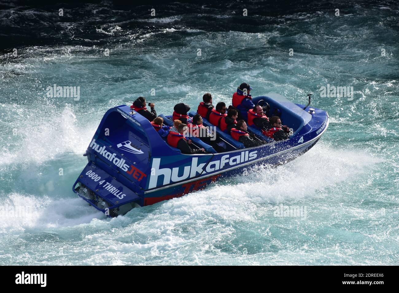 Tourist jet boat of Huka Falls riding fast through rough water of Waikato River. Stock Photo