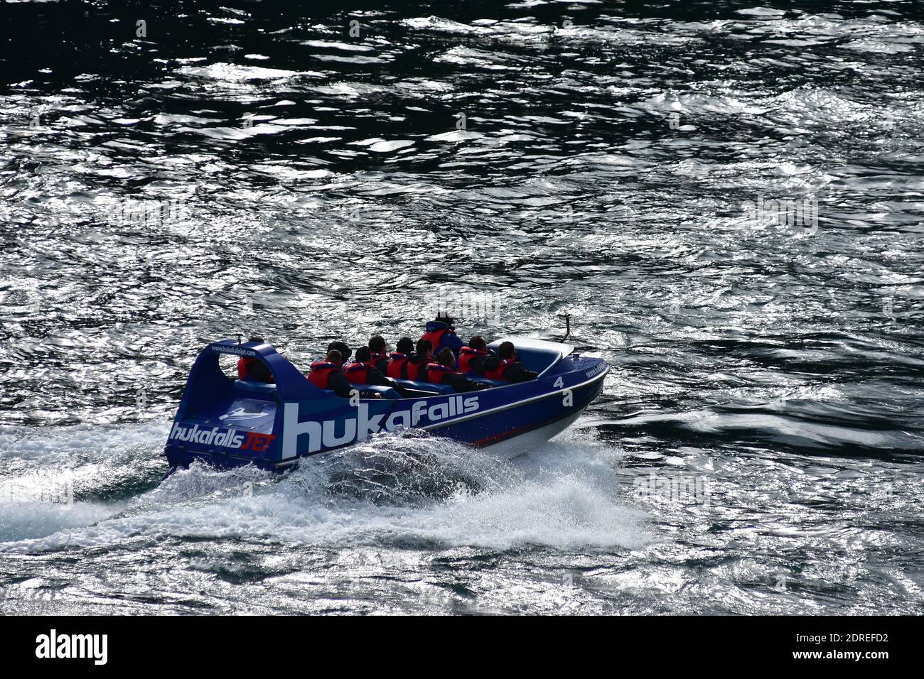 Tourist jet boat of Huka Falls taking off on white water in back light. Stock Photo