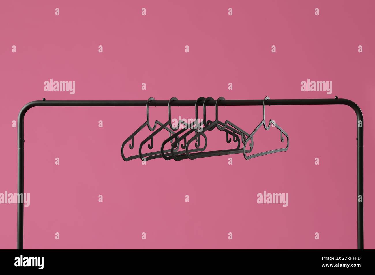 Rack with clothes hangers on color background Stock Photo - Alamy