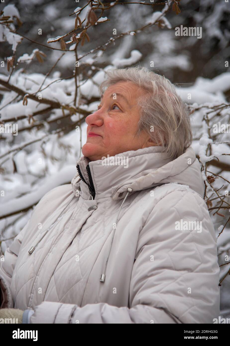 An elderly woman with gray hair in a light jacket on a walk in the ...