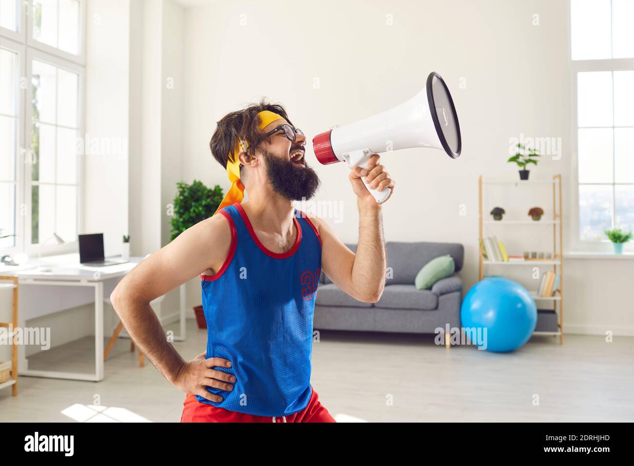 Sports fan cheering in megaphone, supporting favorite team or announcing fitness goods sale Stock Photo