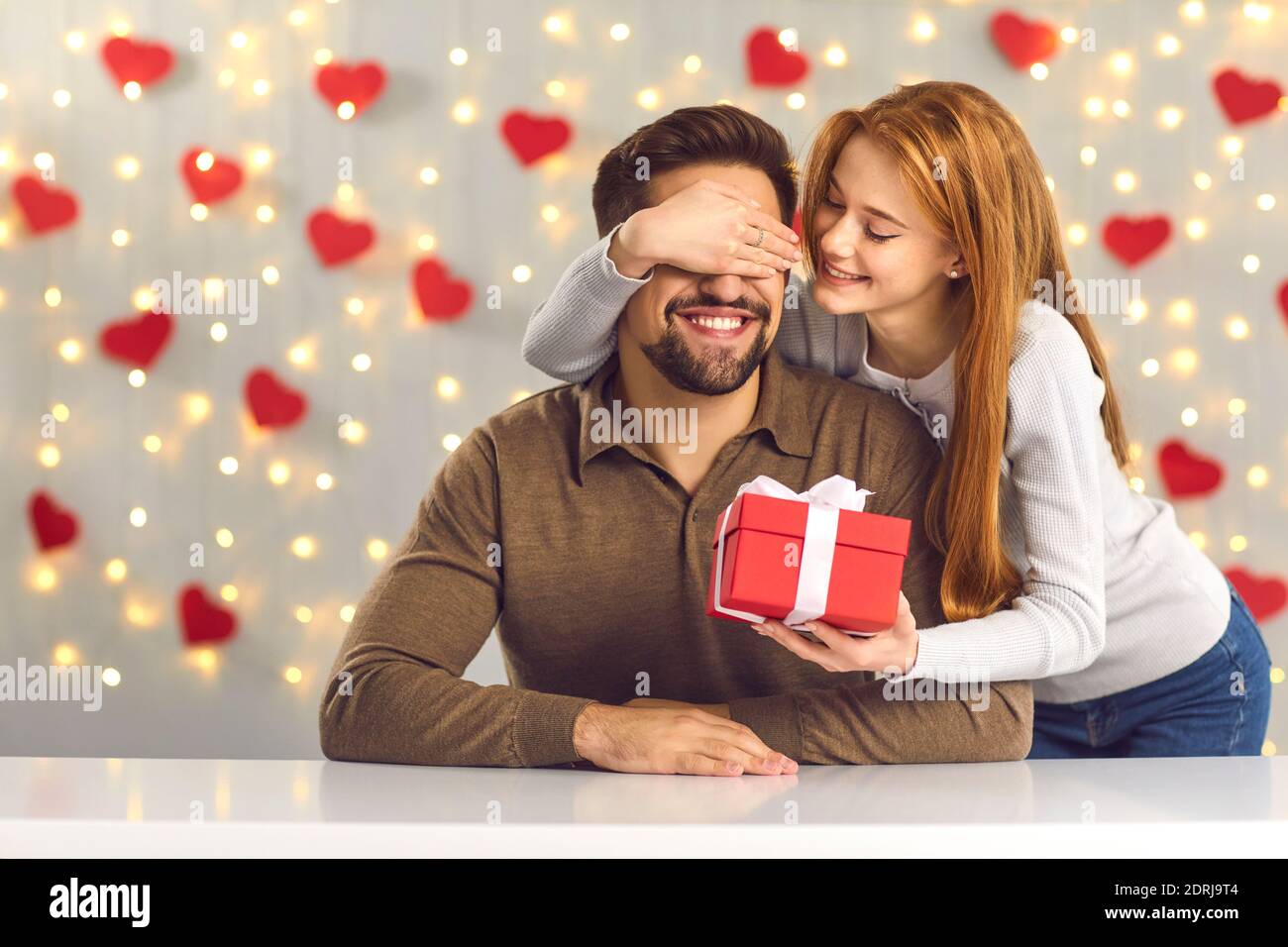 Happy young man getting present from his loving girlfriend on Saint