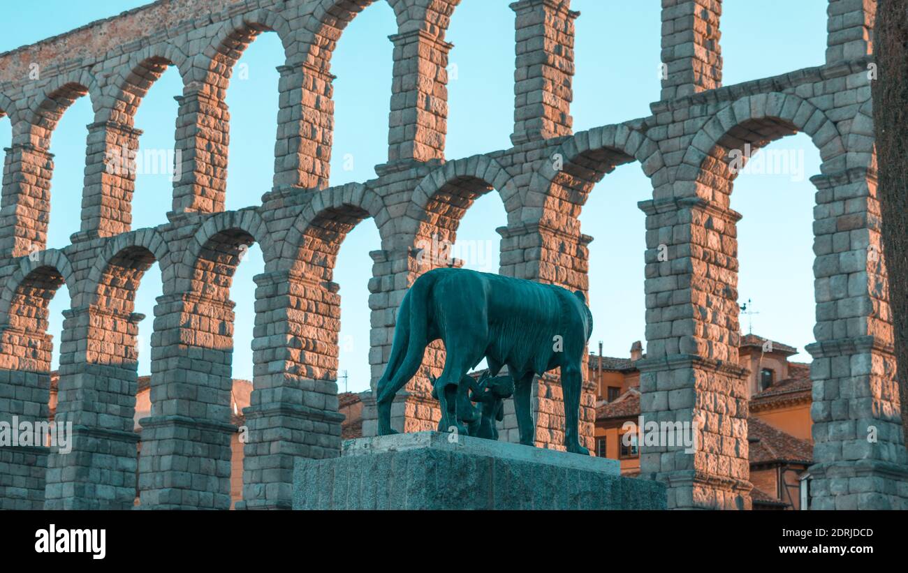 SEGOVIA, SPAIN - Feb 23, 2020: Frontal view at sunset of the aqueduct of Segovia (Spain) with a sculpture of Romulus and Remus in the foreground. Stock Photo