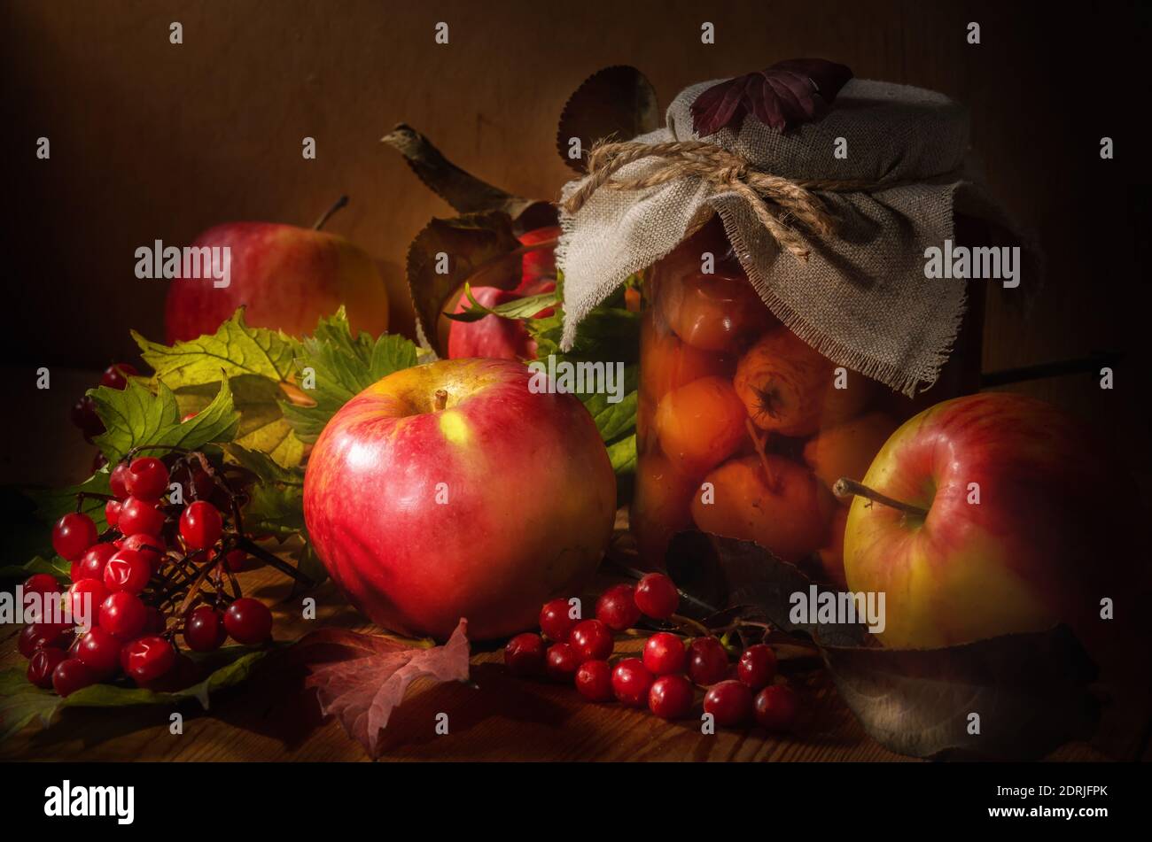 apples and branches of viburnum on a dark wooden background in a rustic ...