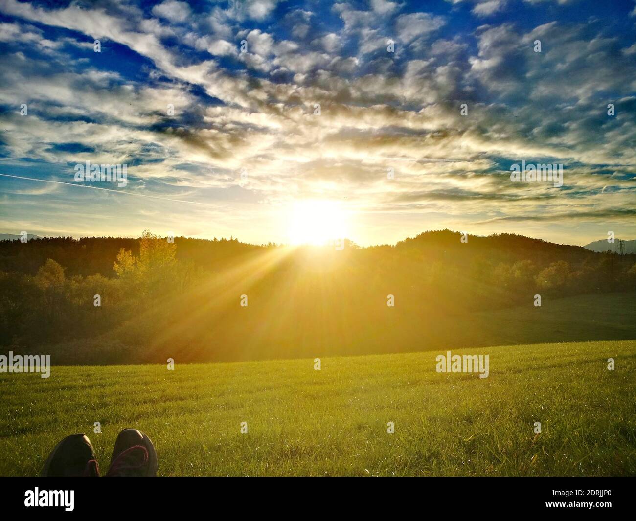 Low Section Of Person On Field Against Sky During Sunset Stock Photo