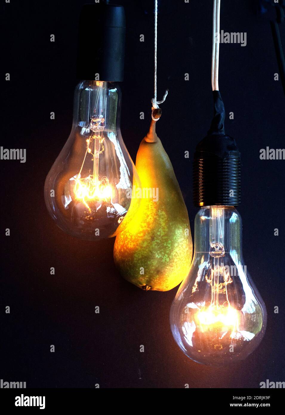 Close-up Of Light Bulb And A Pear Hanging Against Black Background Stock  Photo - Alamy