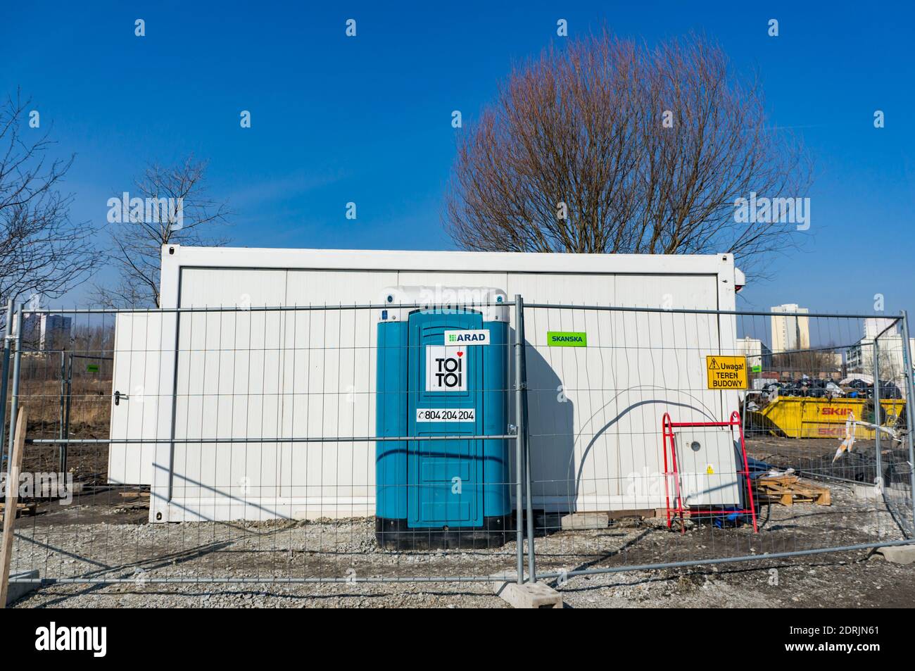 POZNAN, POLAND - Mar 11, 2018: Toi Toi portable toilet and container on a construction area behind a metal fence Stock Photo