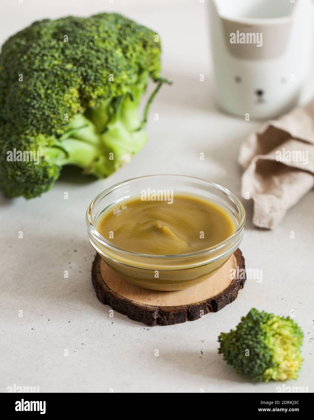The first lure for children. Baby puree with broccoli in a transparent plate with fresh broccoli. Layout.  Stock Photo