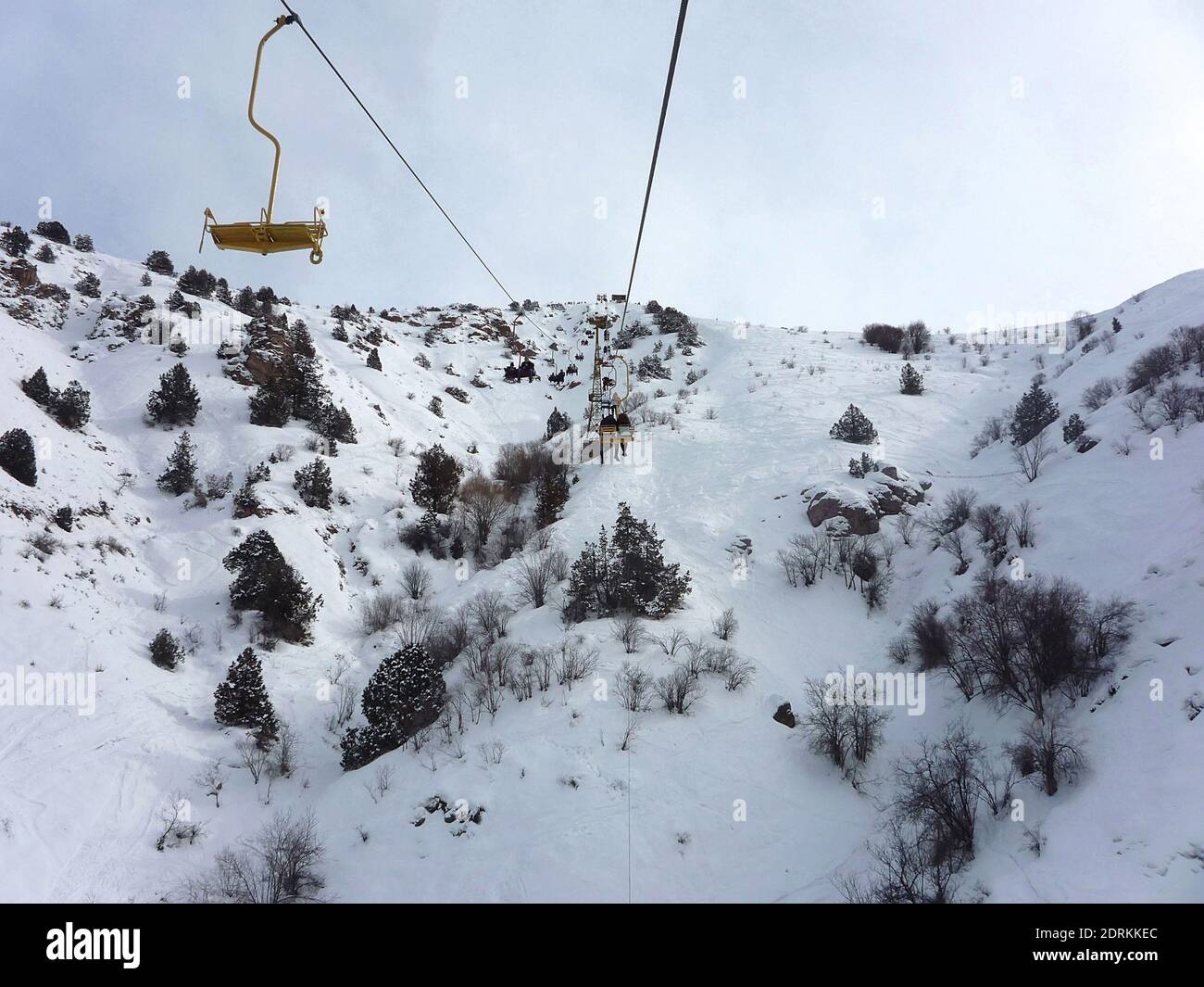 People climb up the mountain on a cable car in winter in the snowy Chimgan mountains Stock Photo