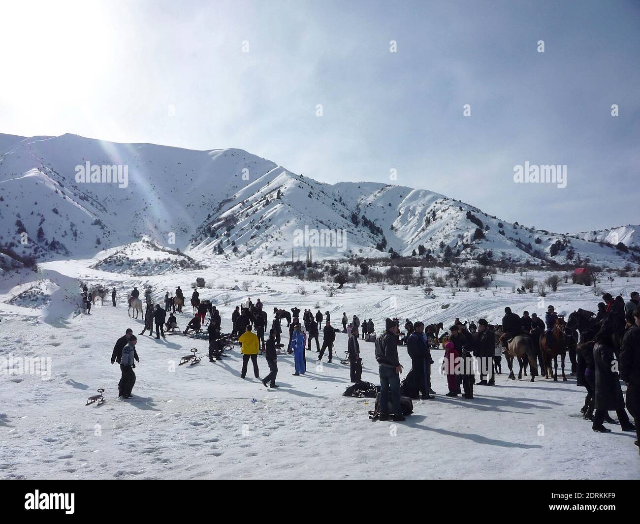 Snow-covered Chimgan mountains on a sunny day, many people sledding and riding horses, Uzbekistan Chimgan Mountains, December 2019 Stock Photo