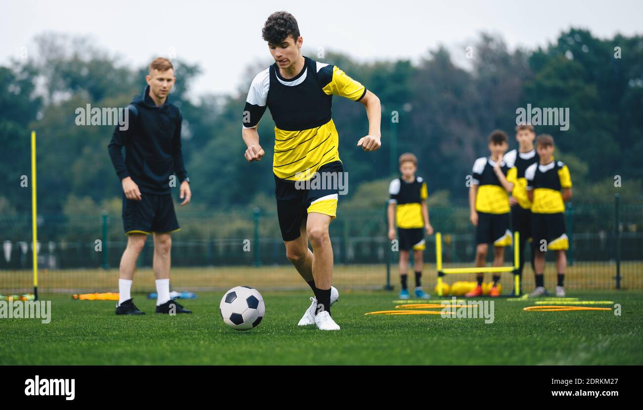 Youth Sports Player Running on Training Field. Junior Football Club Practice Session. Teenagers in Soccer Training Sportswear with Young Coach. Sports Stock Photo