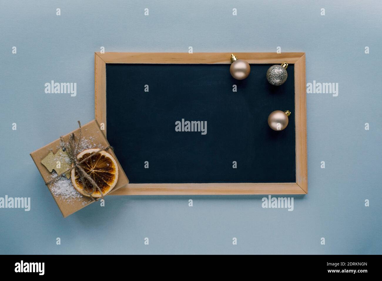 Chalkboard, gift in a box and Christmas decorations, top view, flat lay. Mock up. Stock Photo