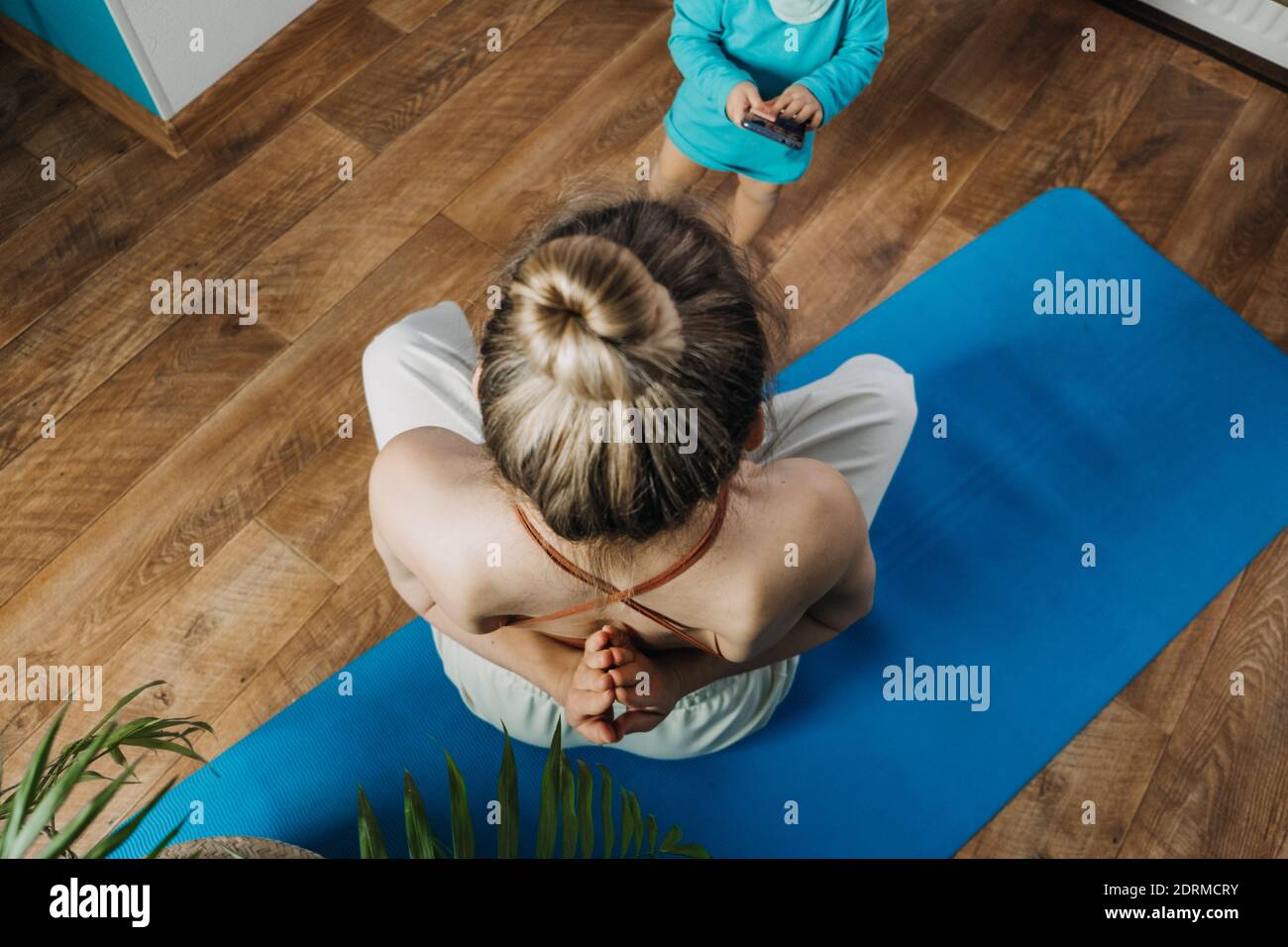 Young mother sitting on the floor, enjoy meditation do yoga exercise at home with his little daughter baby girl. Mental health, self care, No stress Stock Photo