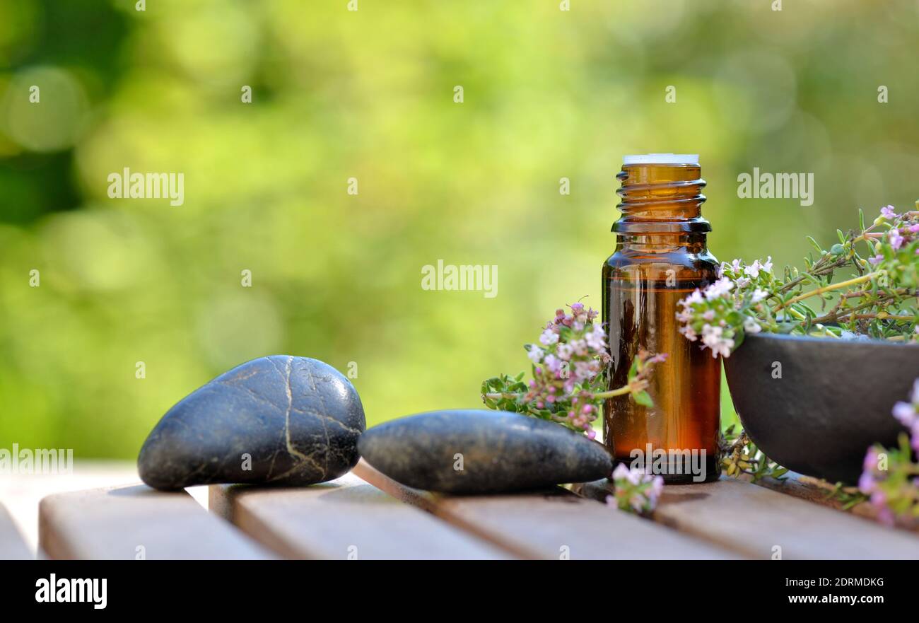 bottle of essential oil on a  table in garden with pebbles and aromatic plant Stock Photo
