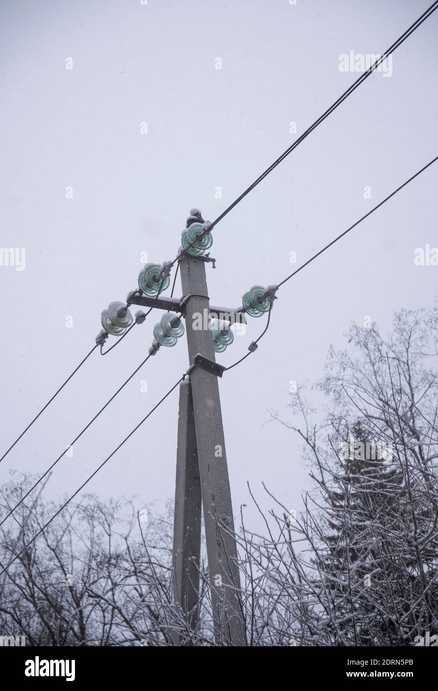 Power line sprinkled with snow against the background of a cloudy sky on a winter day. Stock Photo