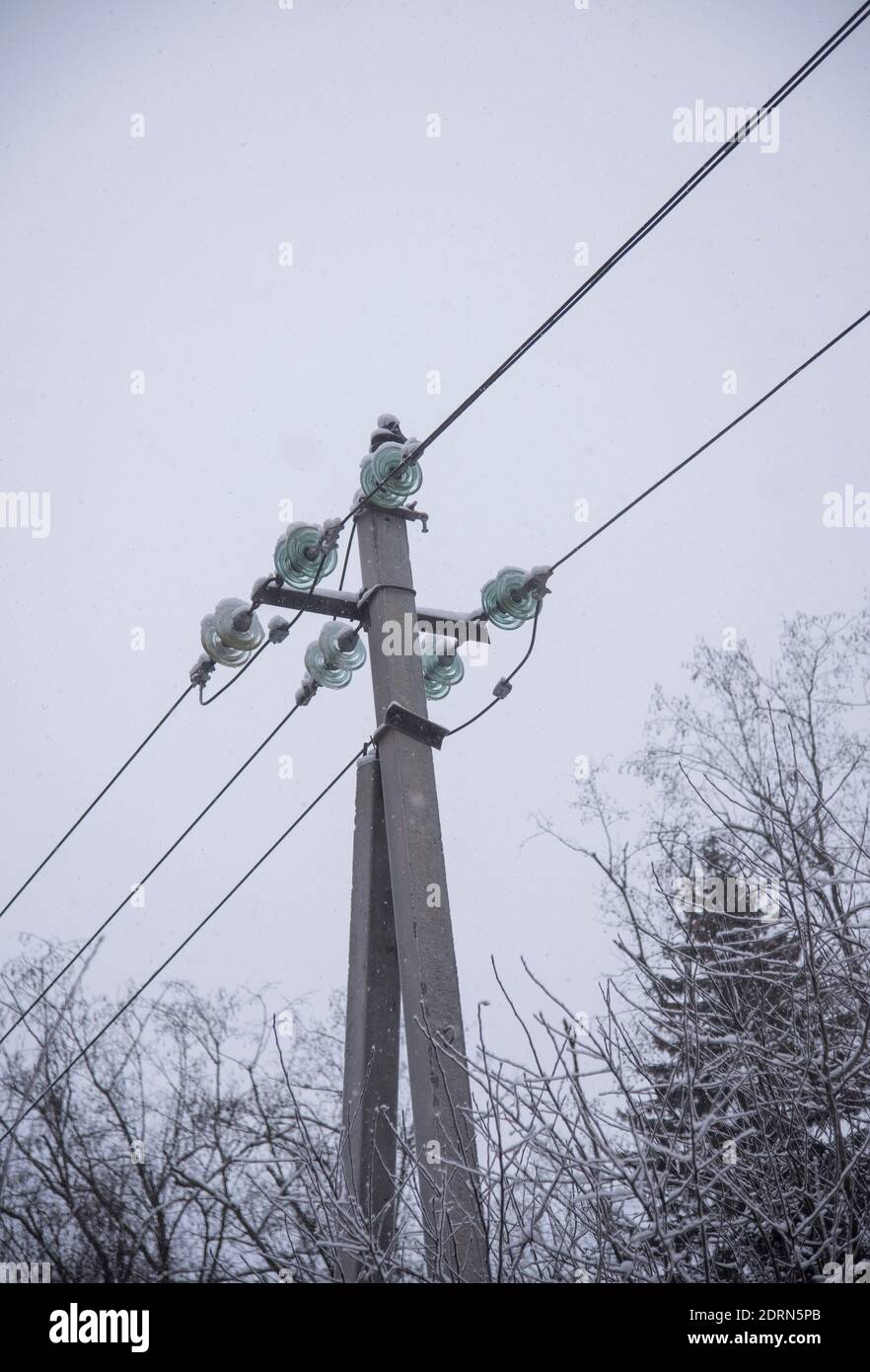 Power line sprinkled with snow against the background of a cloudy sky ...