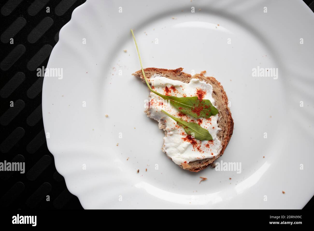Healthy yeast free piece of bread with sour cream and arugula served Stock Photo