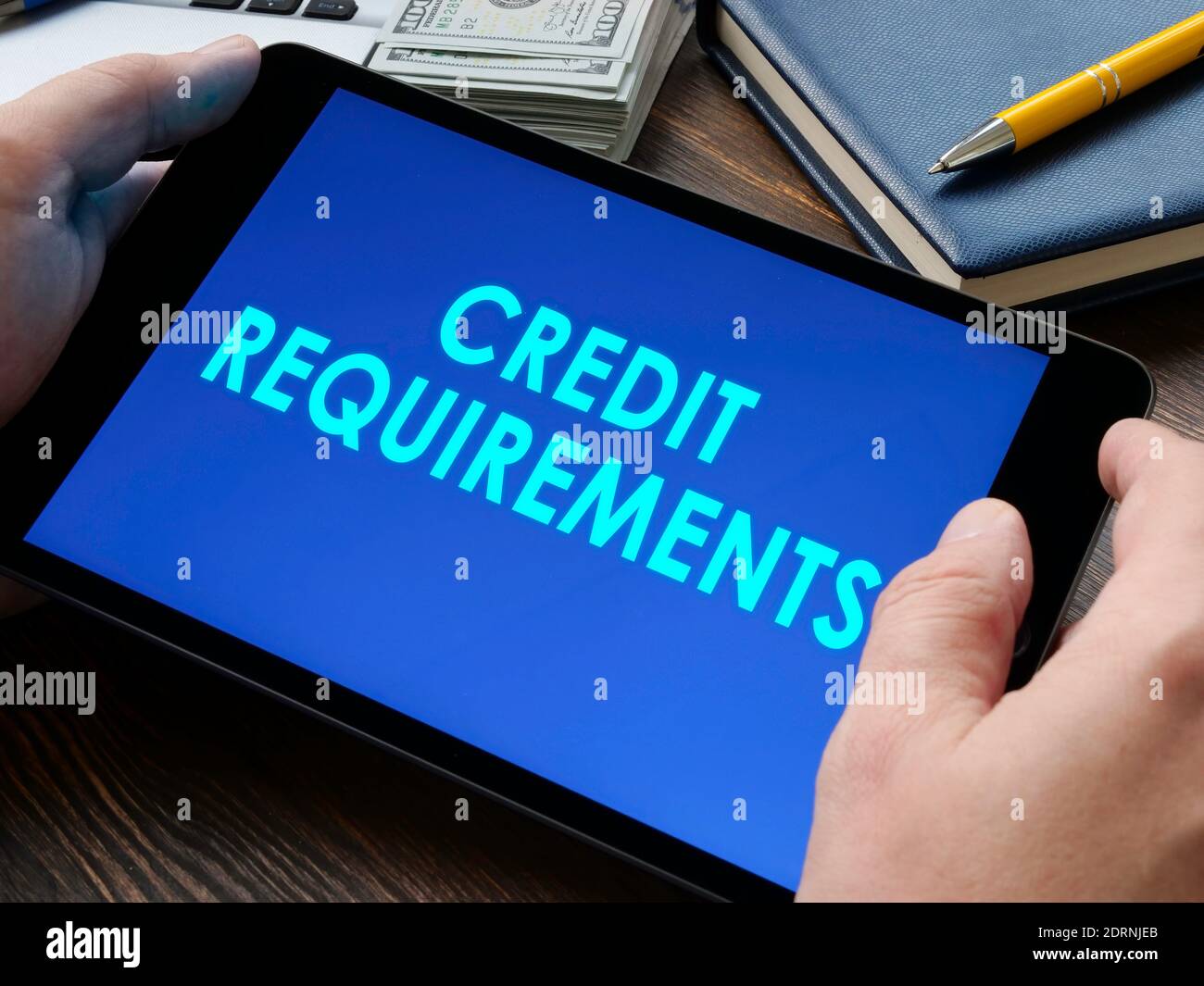 Man reads on the tablet about the credit requirements. Stock Photo