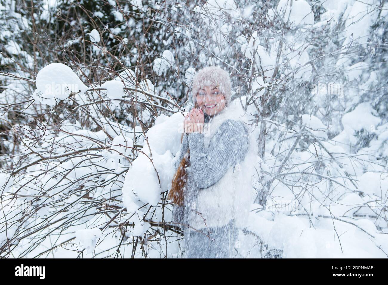 Beautiful smiling young woman under falling snow in wintertime outdoors Stock Photo