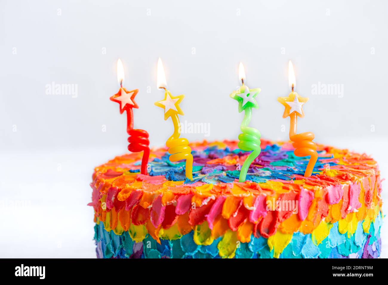Multicolored birthday cake decorated with burning candles in the form of  stars. Happy fourth birthday concept Stock Photo - Alamy