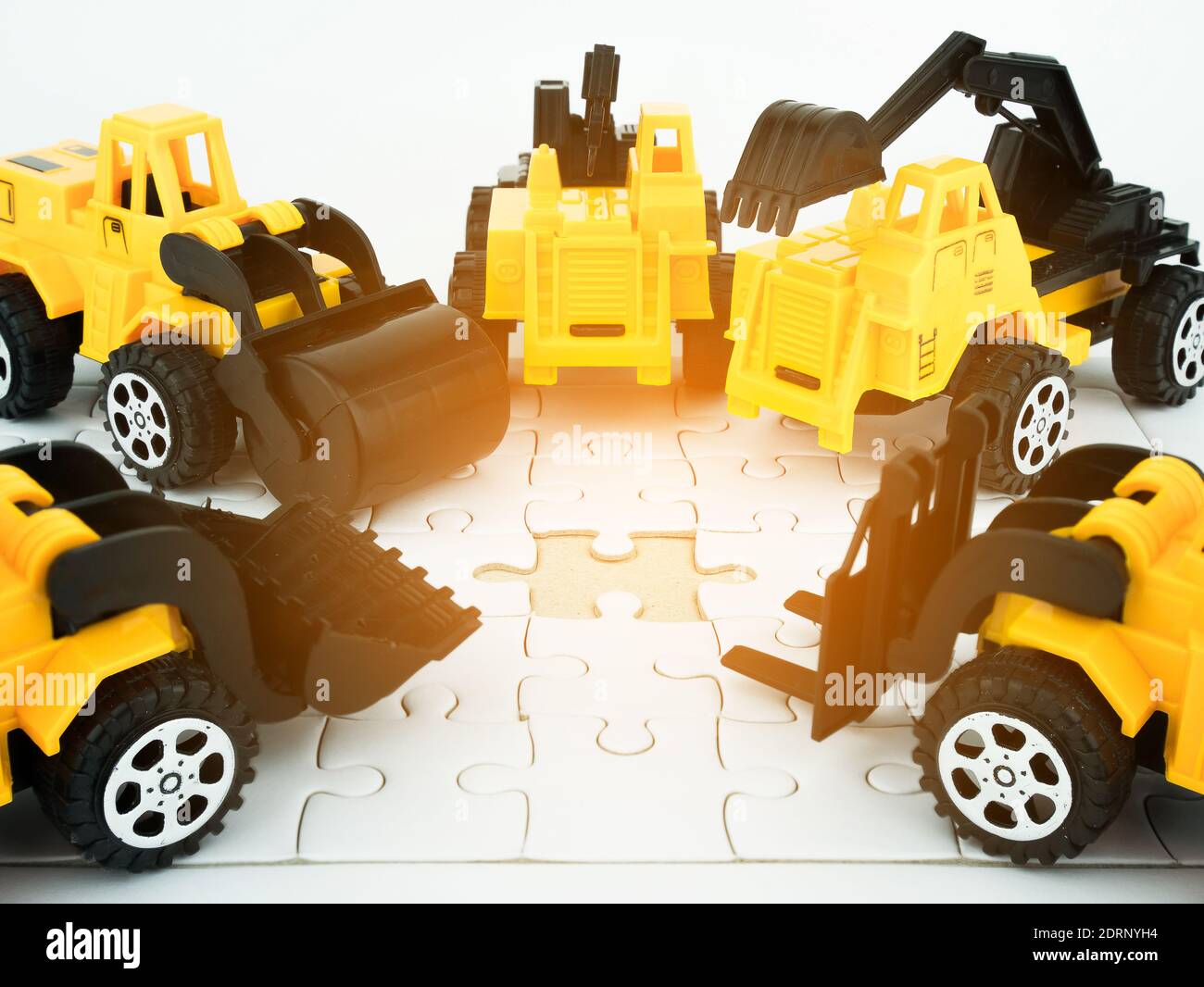 Toy Bulldozers On Jigsaw Pieces Against White Background Stock Photo